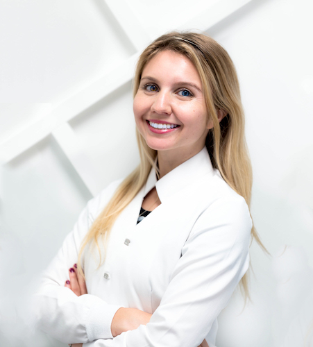 Blonde woman with a white blouse smiles with dental implants at Elevate Smile Design