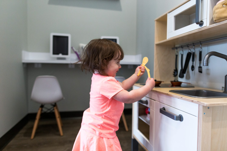 A brunette little girl plays in the kids area at Elevate Smile Design