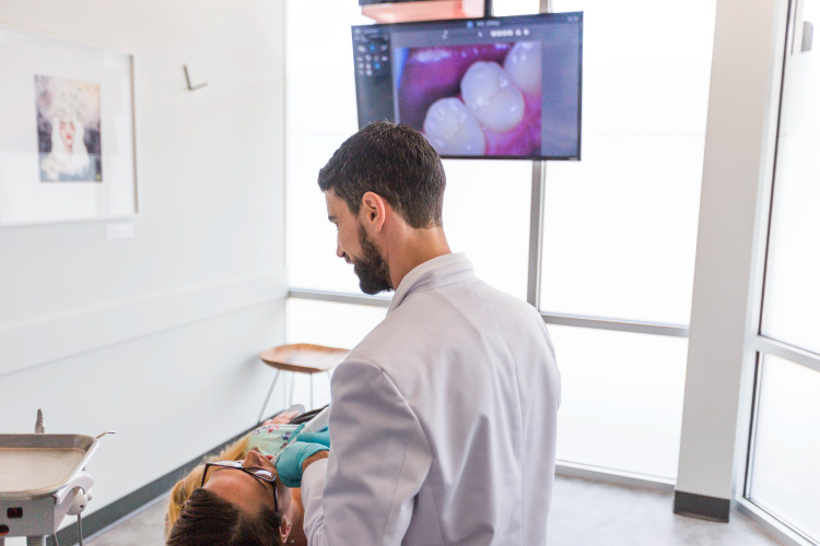 Dr. Perlman examines the mouth of a female patient with a toothache at Elevate Smile Design