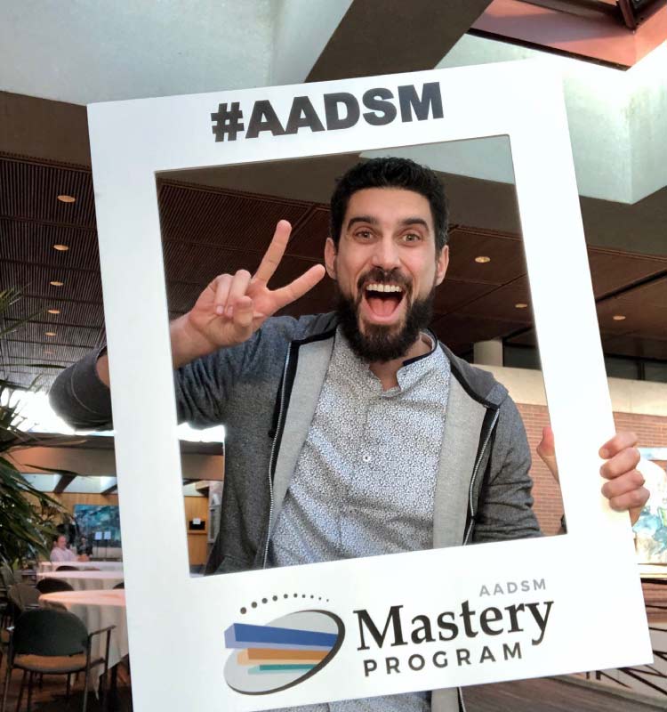 Dr. Perlman smiles and make a peace sign through the #AADSM sign in Chicago while studying sleep breathing disorders