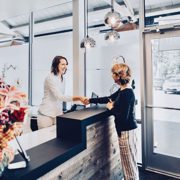 Patient at the front desk of Elevate Smile Design asking about dental implants