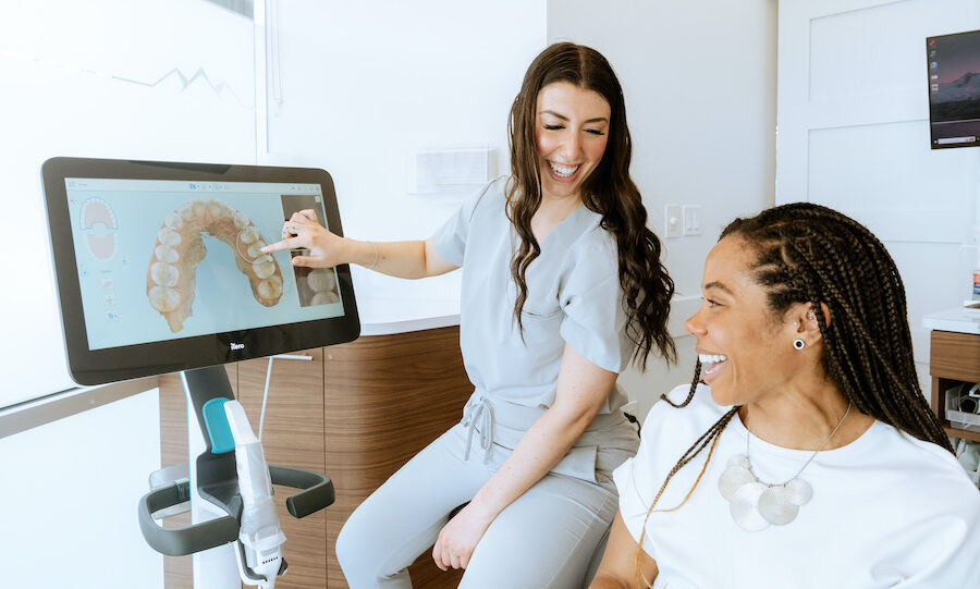 A brunette dental assistant shows a patient a preview of her teeth with Invisalign